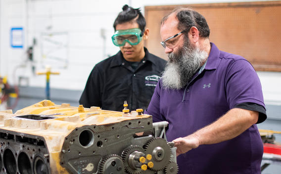 Diesel technology student and professor examining engine