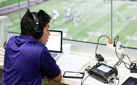 Sports media student recording commentary at Butler football game