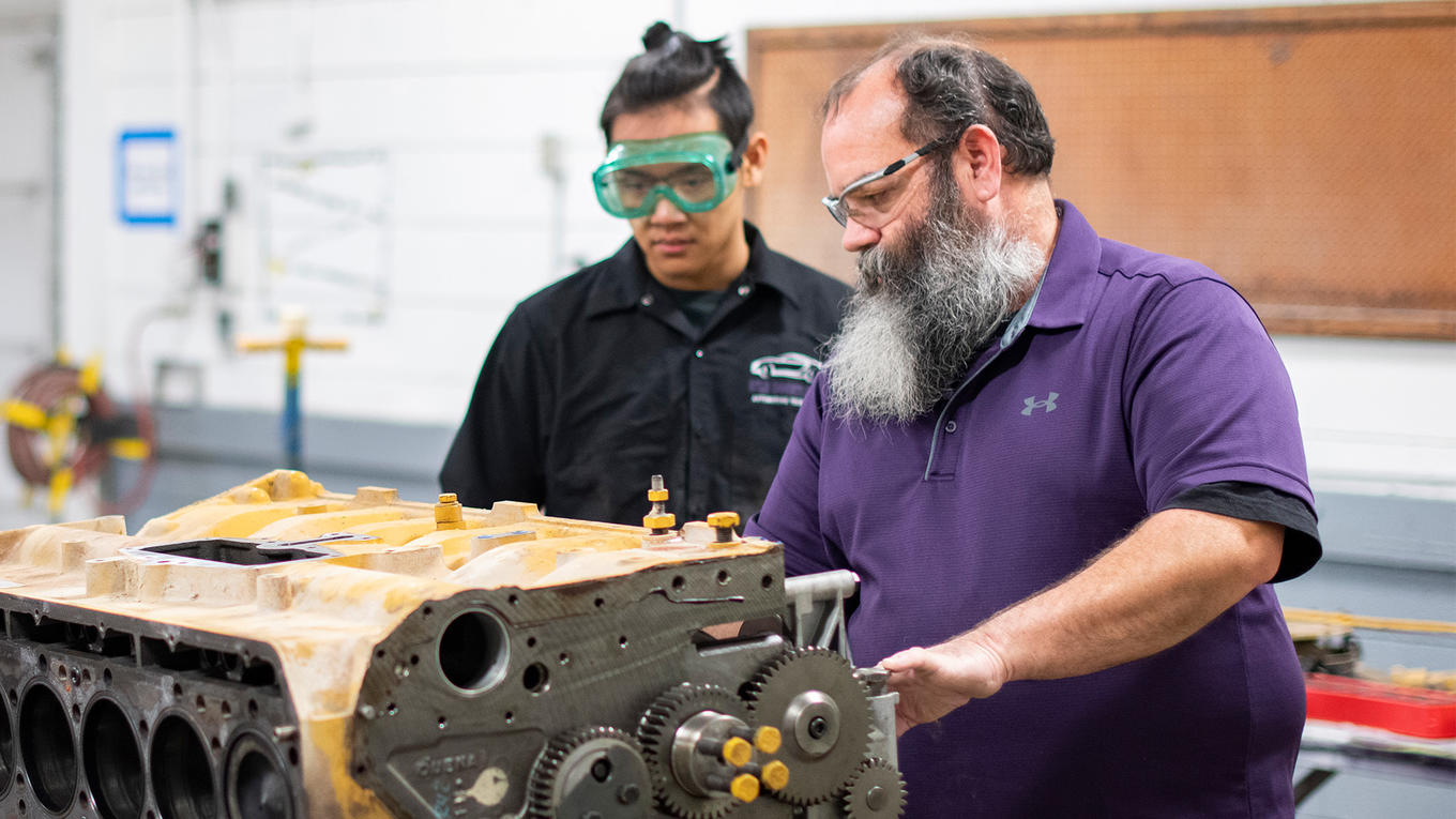 Diesel tech instructor shows student a part of a diesel engine